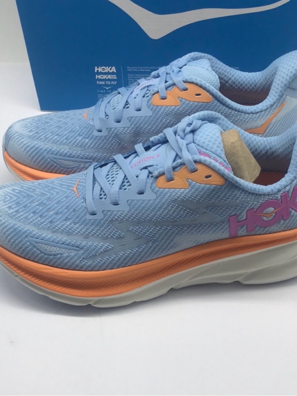 Hoka Light Blue Running Shoe with Orange Trim and Pink Logo
